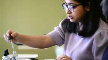 Nabanita Das, a student in the University of Maine's School of Forest Resources, puts drops of oil ontp a paper plate with a pulp-based coating to show how it prevents the oil from soaking in. Das and a group of University of Maine, Orono, researchers are developing alternatives to the unhealthy PFAS coatings that had been used to keep oil from soaking into single-use paper plates.